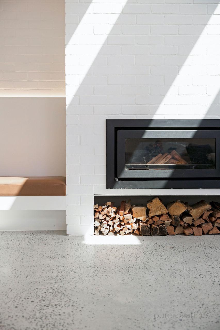 Fireplace with painted white brick surround and polished concrete floors, Sydney location house