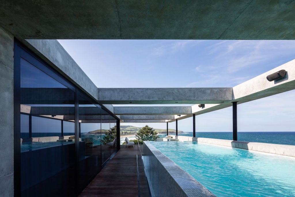 A pool area with concrete structures above in a modern industrial house in Sydney