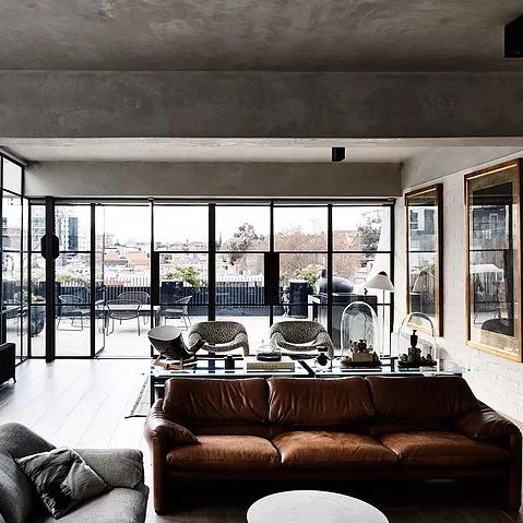 A living room with expansive windows and brown couch in an industrial modern house in Melbourne