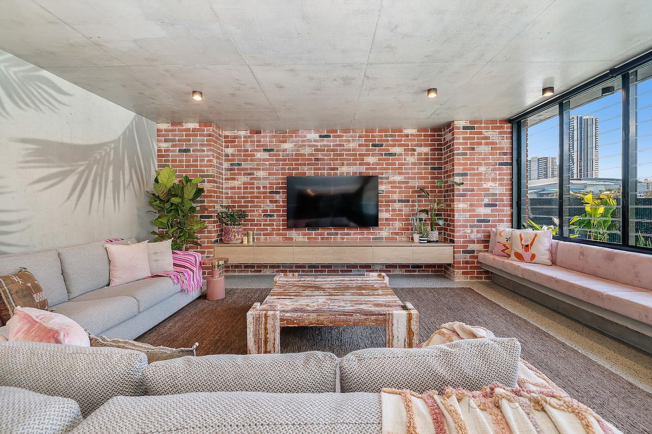 Living area with exposed brick, concrete walls and ceiling with palm tree mural