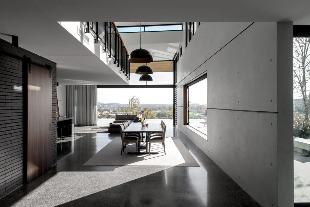 A dining room wth an expansive concrete wall in an industrial modern location house in Brisbane